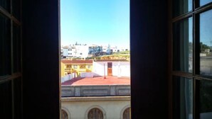 A view through a window with a clear sky, buildings, and a red-roofed structure. - Hotel Luz de Guadiana (Ayamonte)