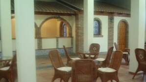 A dining area with wicker chairs and a table, surrounded by white pillars and a tiled floor. - Hotel Luz de Guadiana (Ayamonte)