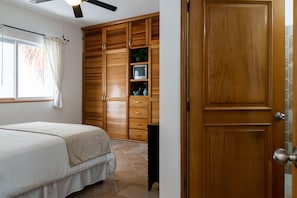 A bedroom with a bed, wooden wardrobe, and a television on a shelf. - Piedra Viva by Playa Paradise (Playa del Carmen)