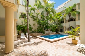 A pool area with a tiled floor, palm trees, and lounge chairs. - Piedra Viva by Playa Paradise (Playa del Carmen)