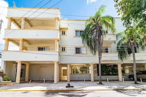 A multi-story building with balconies, a gated entrance, and a parking area. - Piedra Viva by Playa Paradise (Playa del Carmen)