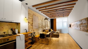 A modern kitchen with wooden beams, a dining area with a wooden table and chairs, and a brick wall. - RIS Dalma Collection Yerevan (Yerevan)