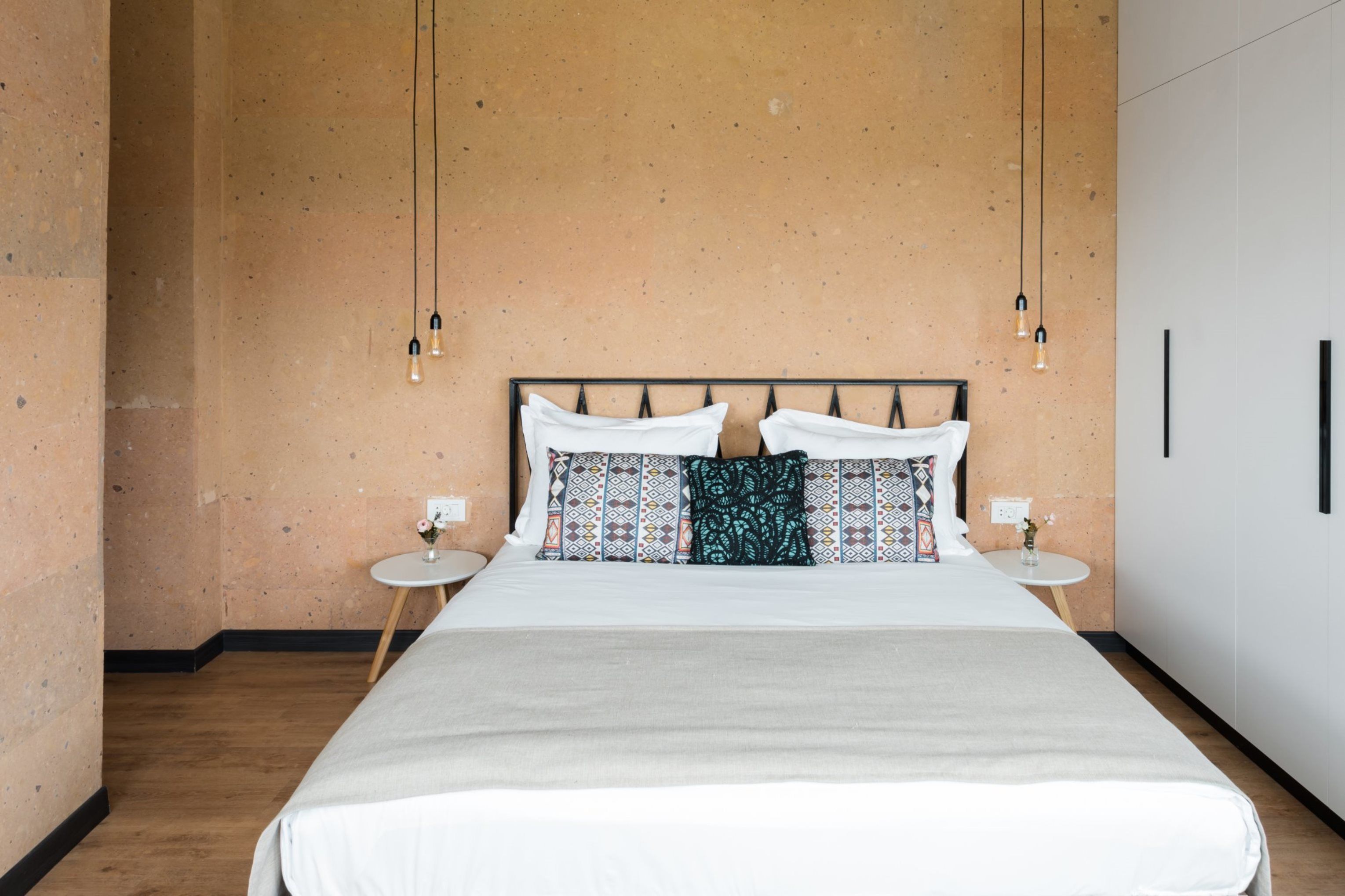 Un dormitorio moderno con una cama grande, almohadas estampadas y lámparas colgantes.