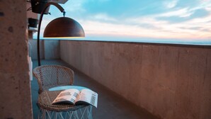 A balcony with a wicker chair and an open book, a hanging lamp, and a view of the sky. - RIS Dalma Collection Yerevan (Yerevan)