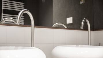 A bathroom with two sinks, a towel rack, and a mirror.