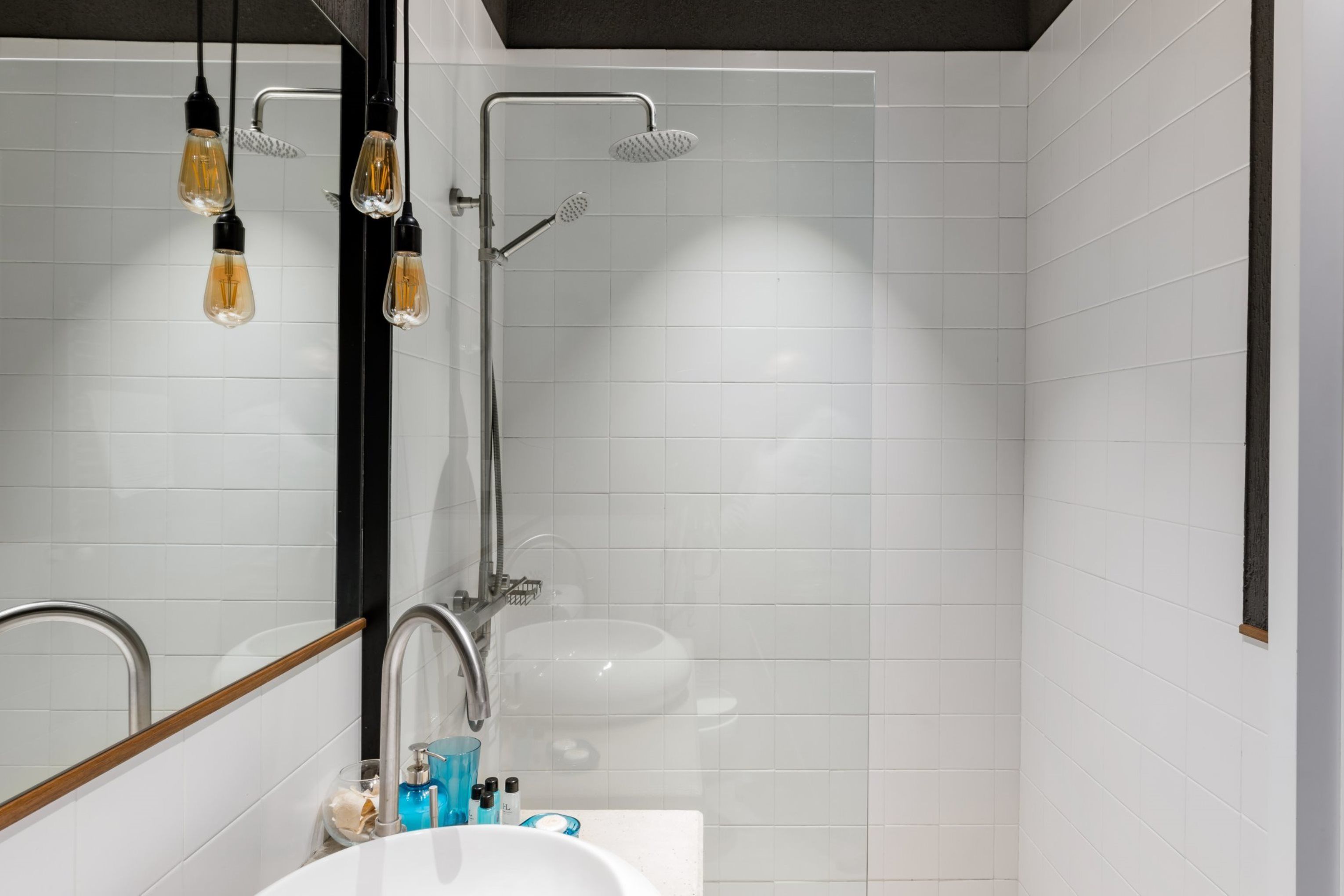 Un baño moderno con lavamanos, espejo y ducha blancos.