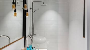 Un baño moderno con lavamanos, espejo y ducha blancos.