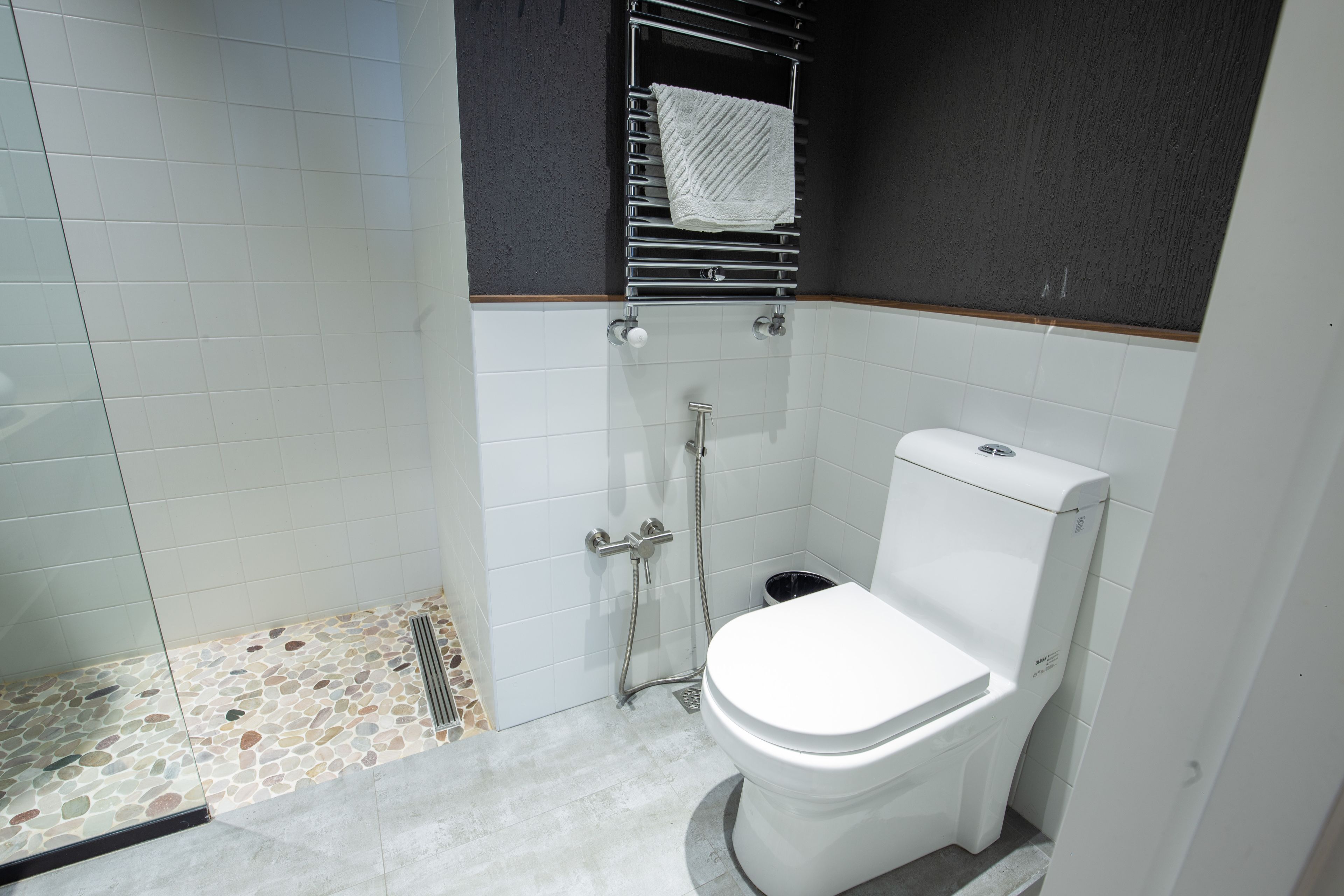 Een badkamer met een wit toilet, een douche met een glazen deur en een betegelde vloer.