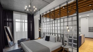A modern bedroom with a large bed, a small side table, a mirror, and a partition wall with a grid pattern. - RIS Dalma Collection Yerevan (Yerevan)