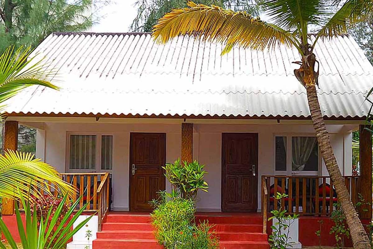 Una casa de dos pisos con fachada roja, techo blanco y un porche con barandillas de madera.