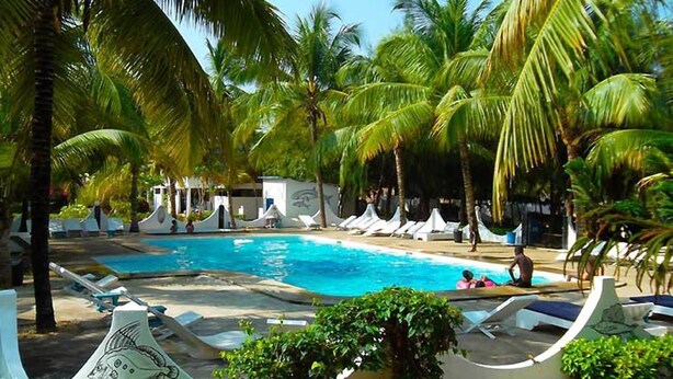 A pool area with lounge chairs and palm trees. - Hotel Awalé Plage - Village vacances (Grand Popo)