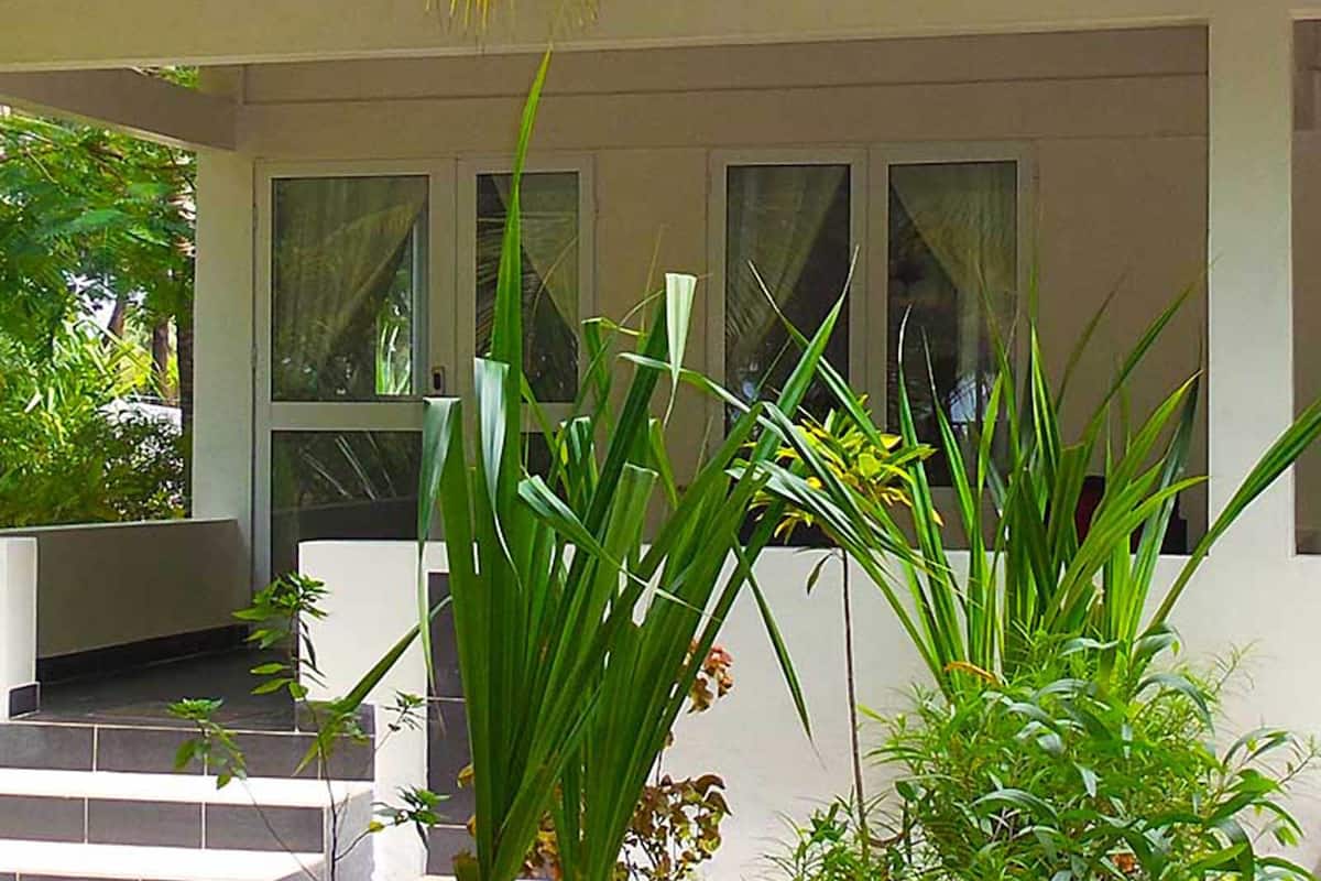 Un edificio con fachada blanca, ventanas amplias y una zona de entrada con mosaicos y escalones.