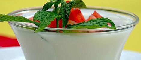 A clear glass dessert with a mint garnish and watermelon pieces.