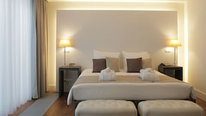 Habitación de hotel con una cama grande, dos mesitas de noche, una lámpara y una bata sobre la cama.