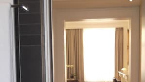 Un pasillo con suelo de madera que conduce a una habitación con un ventanal y cortinas.