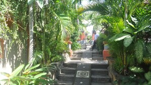 A stone staircase surrounded by lush greenery, leading to a building entrance. - Dewi Sinta Hotel and Restaurant by ABM (Tabanan)