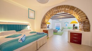 Habitación de hotel con una cama, un escritorio, una lámpara y un arco que da a otra habitación.