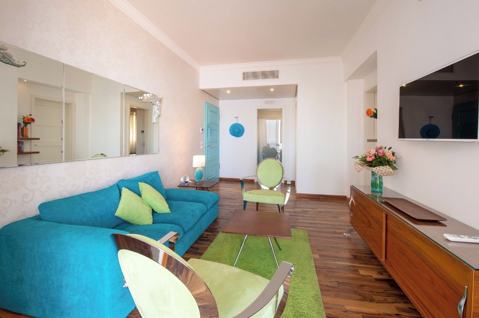 Ein modernes Wohnzimmer mit einer Couch, Sesseln, einem Fernseher und einem Essbereich.