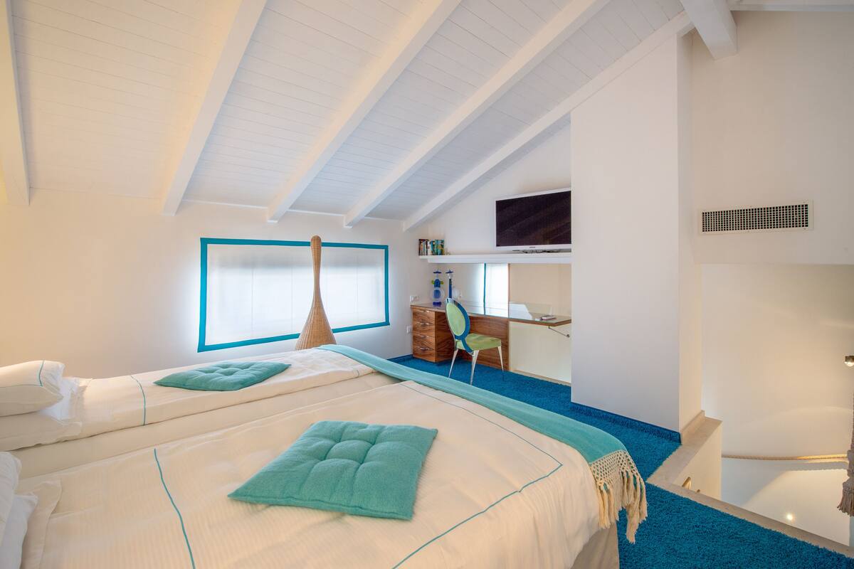 A modern hotel room with a large bed, a desk, and a television.