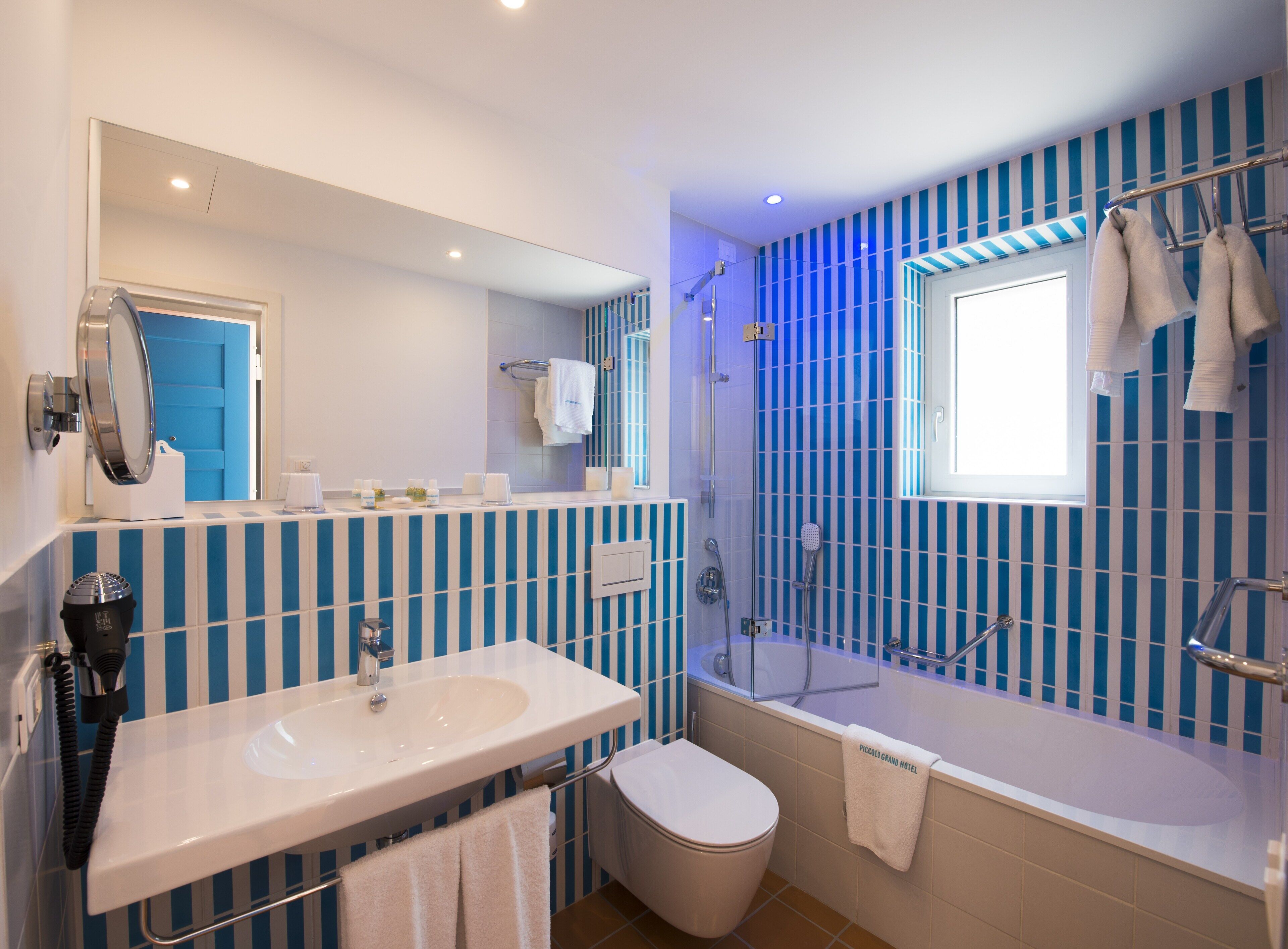 A bathroom with a large mirror, a sink, a toilet, and a bathtub.
