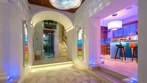 Un interior moderno con una escalera que conduce a una zona de bar, destacando un diseño geométrico en el suelo e iluminación ambiental.