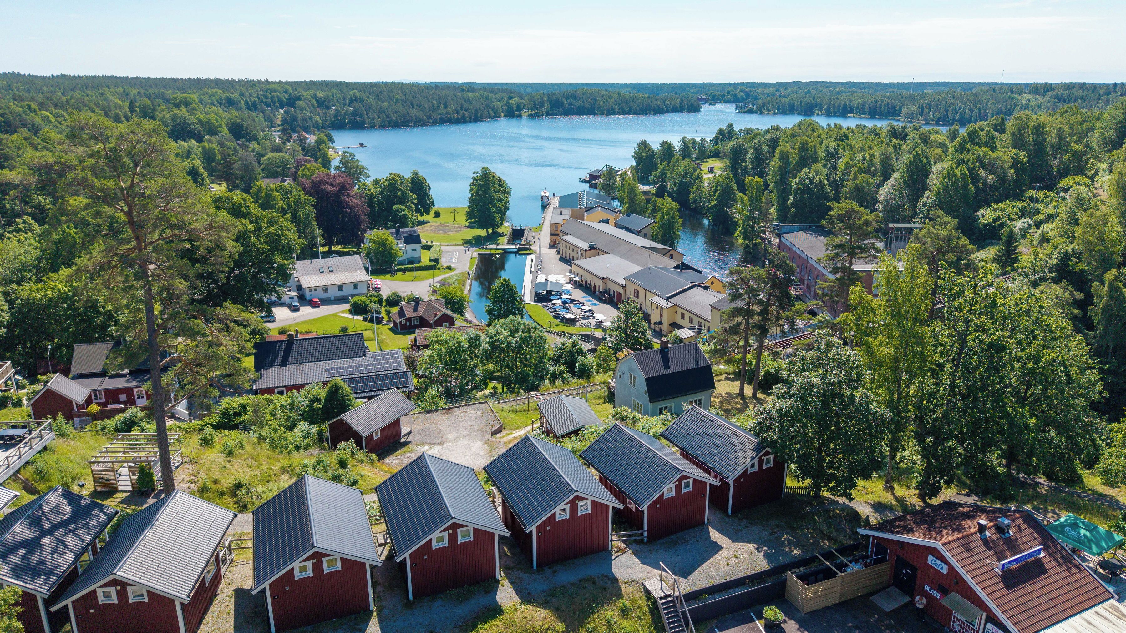 A lakeside resort with red cabins, a dock, and a large building with a glass facade.