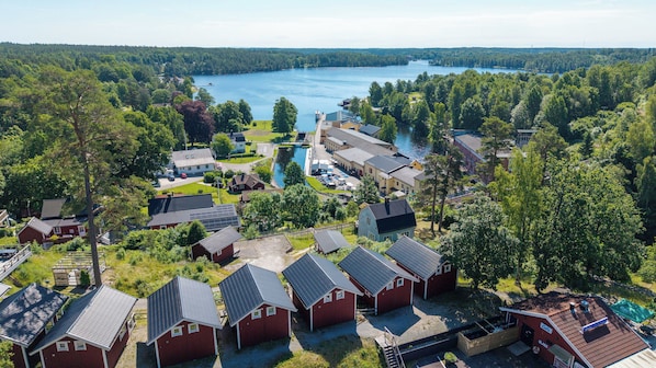 A lakeside resort with red cabins, a dock, and a large building with a glass facade. - The Visitor Stugby (Håverud)