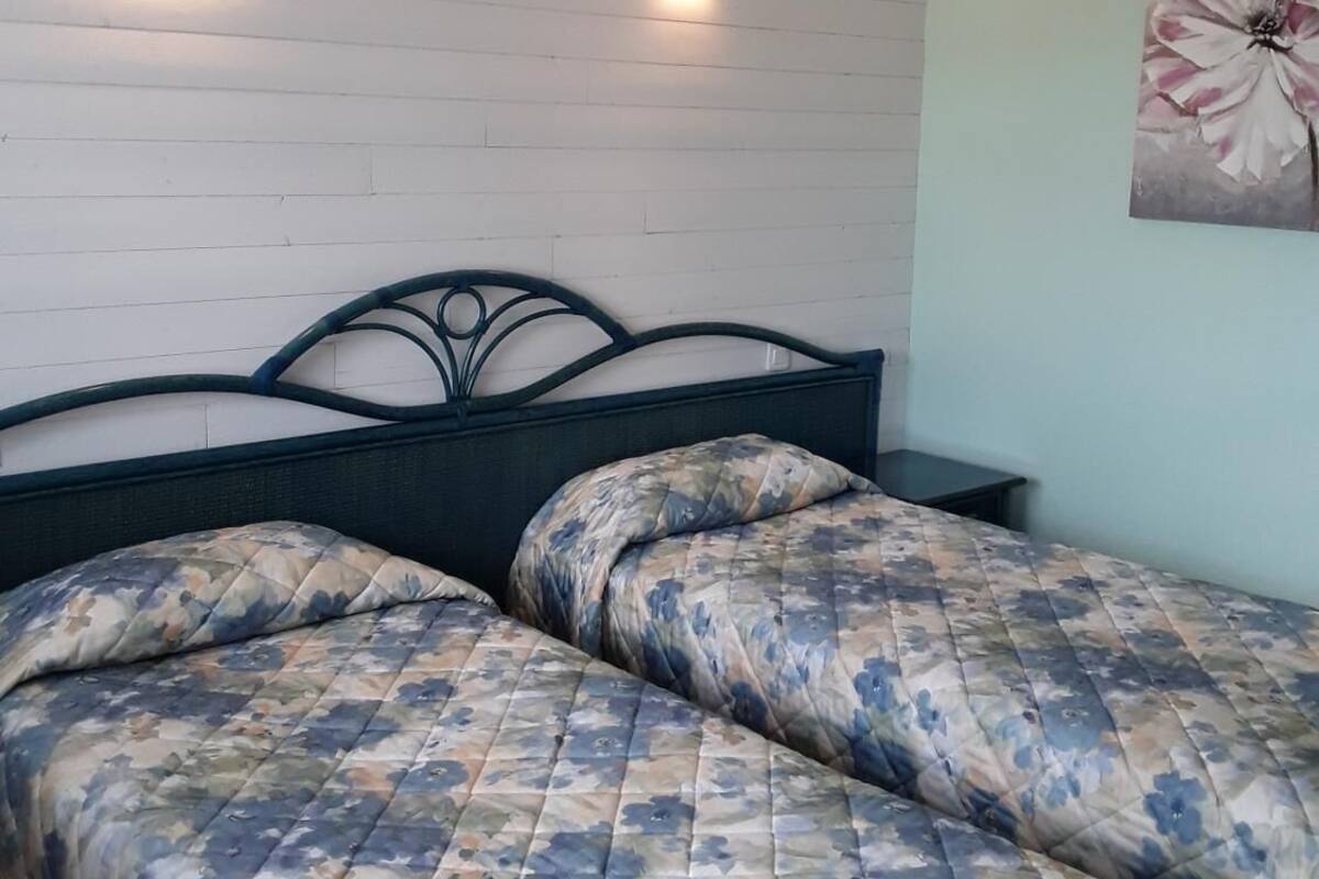 A bedroom with a bed, two wall-mounted lights, and a floral painting on the wall.