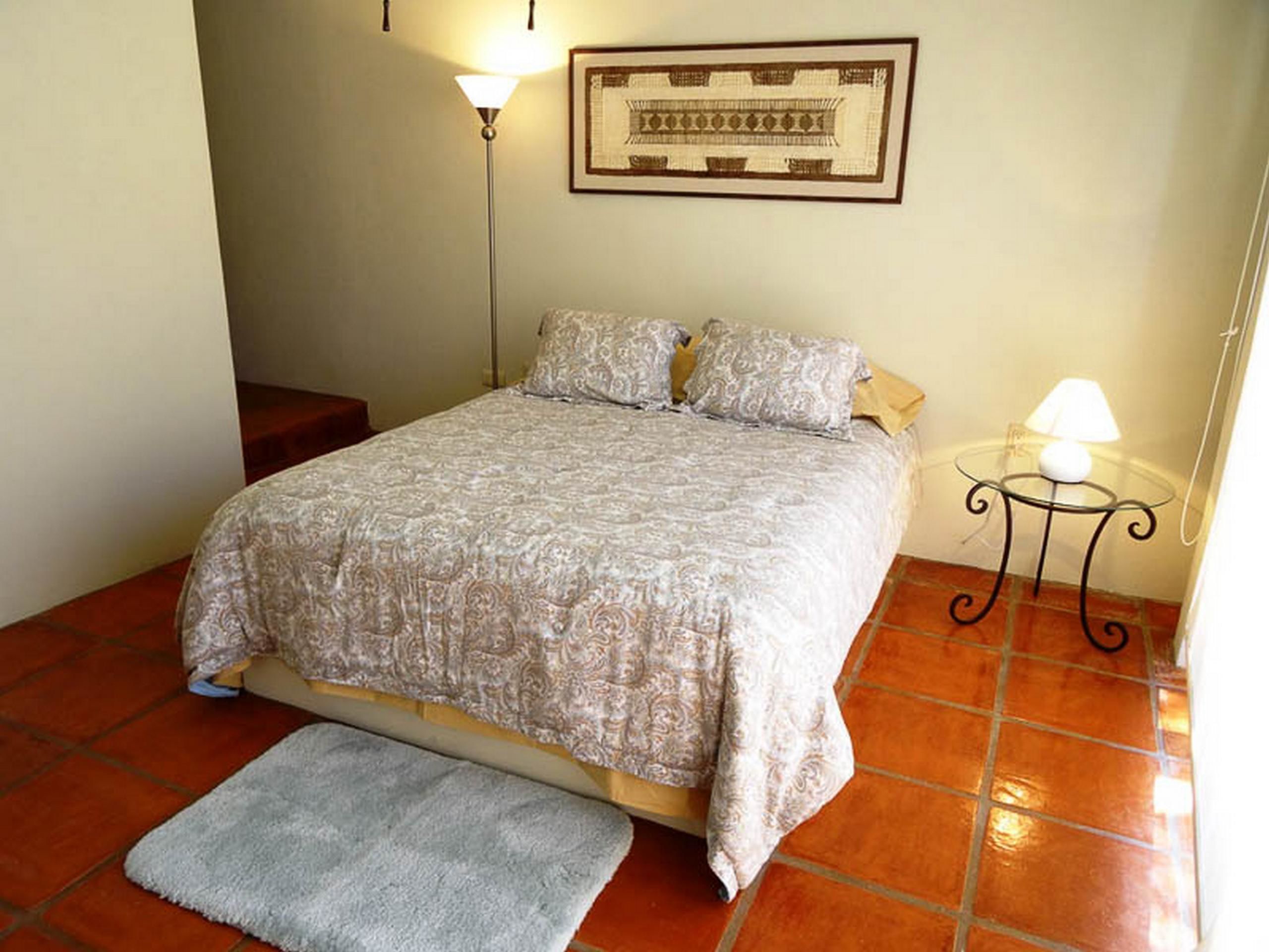Une chambre à coucher avec un lit, une table de chevet, une lampe et un tapis.