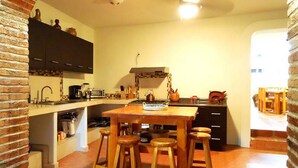 A kitchen with a central island, stools, and a brick wall.