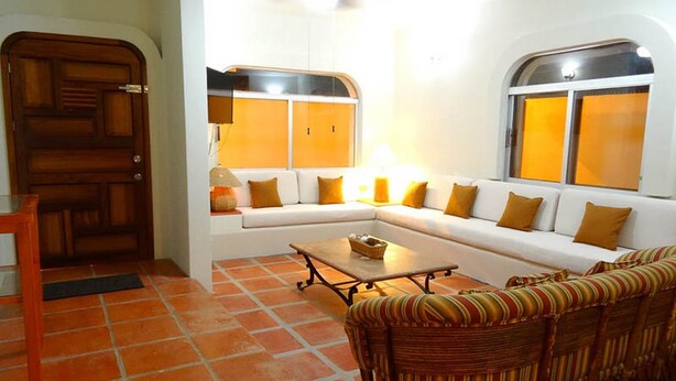 A living room with a sectional sofa, a wicker chair, a coffee table, and a door.