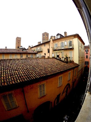 A narrow street with buildings featuring traditional architecture, including a tower and multiple balconies.