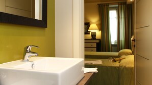 Un baño de hotel con un lavabo blanco, un espejo y una cama verde.