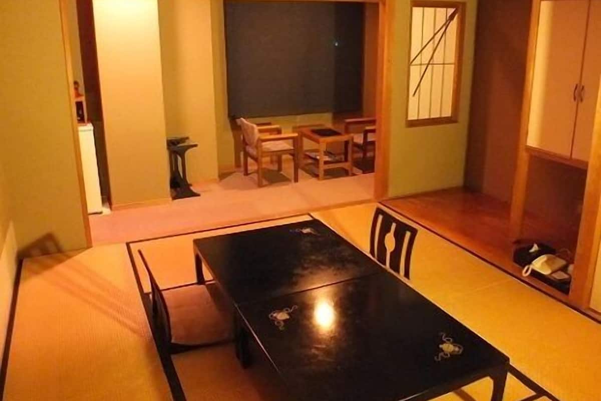 A traditional Japanese-style room with tatami flooring, a black table, and wooden furniture.