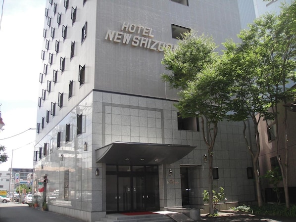 A modern hotel building with a prominent entrance and a sign reading 'HOTEL NEW SHIZUOKU'.