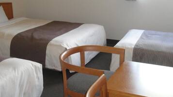 A hotel room with two beds, a wooden chair, and a table.