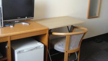A compact workspace with a desk, a chair, a small refrigerator, and a computer monitor.
