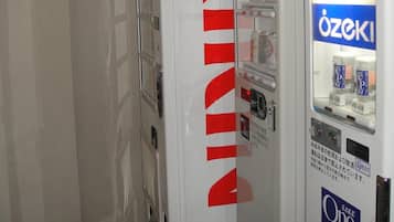 A vending machine with a prominent red logo, a beverage dispenser, and a sign with Japanese text.