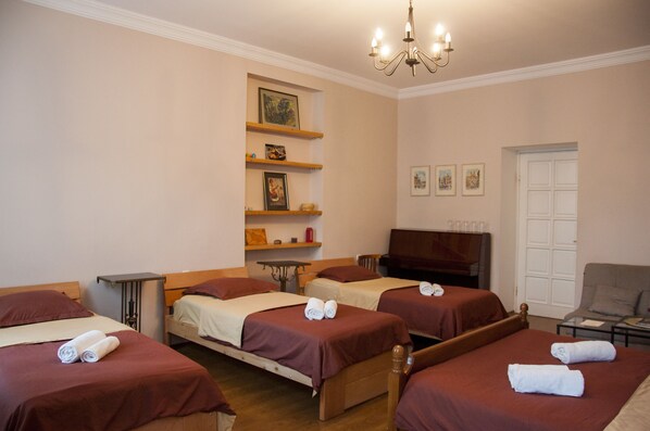 A hotel room with three single beds, a television, a sofa, and a small table. - Guest House Lile (Tbilisi)