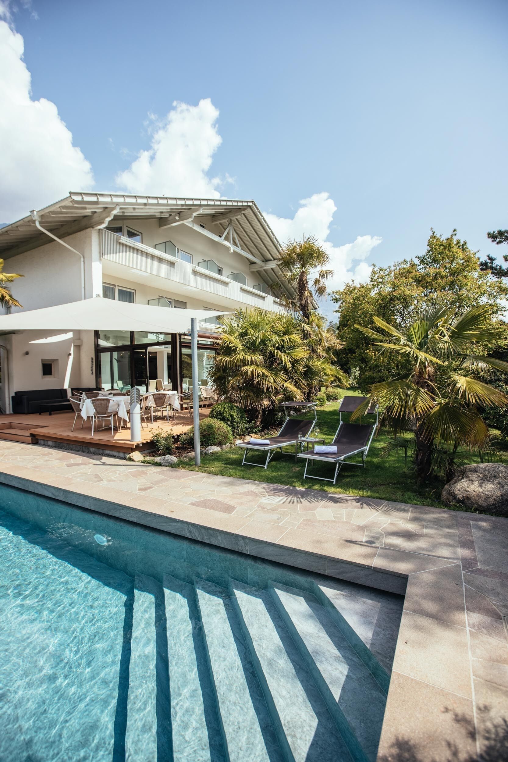 A modern hotel with a swimming pool, outdoor seating, and lush greenery.