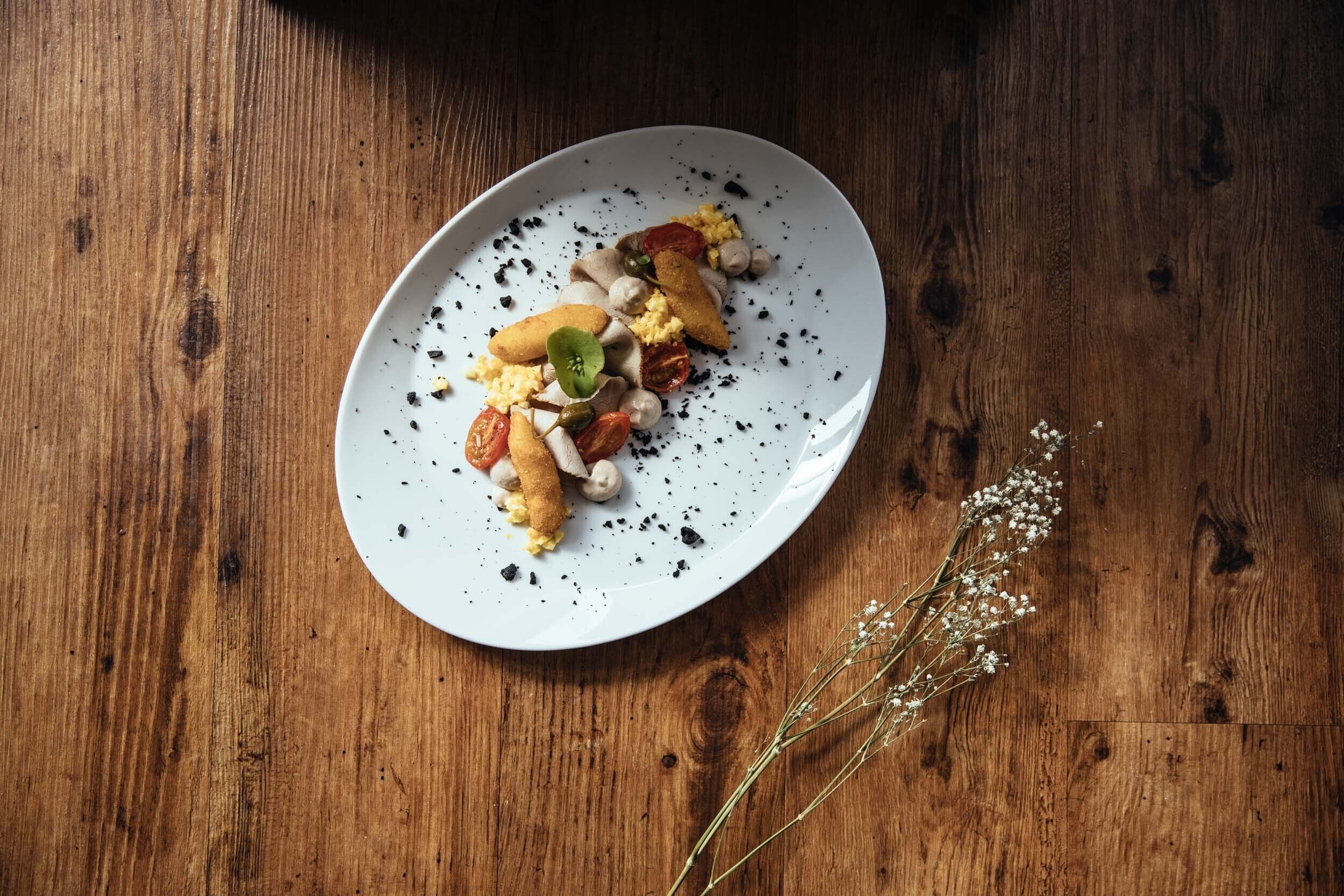 A white plate with food on a wooden table.