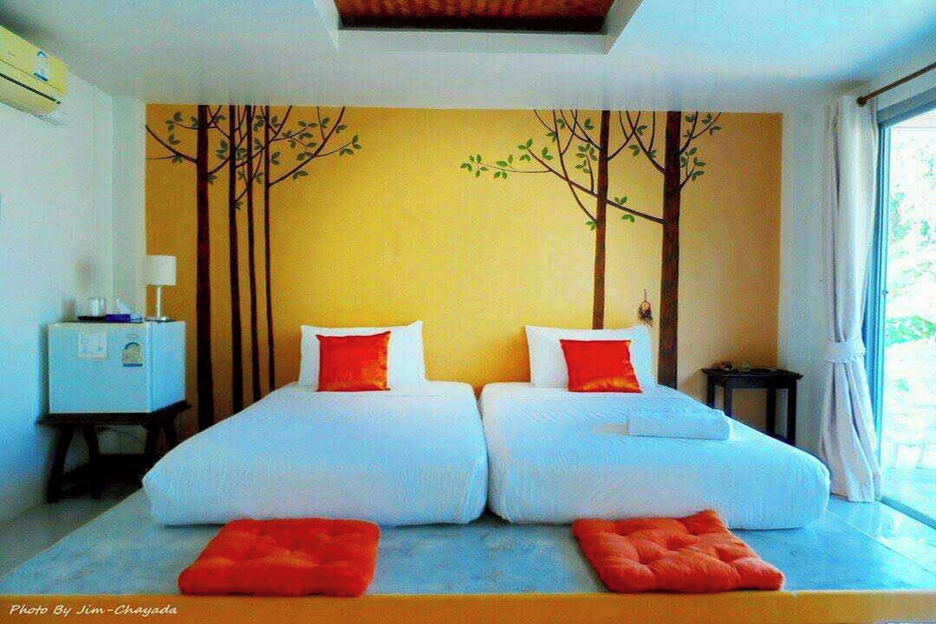 A double room with two beds, a small table, and a wall mural.