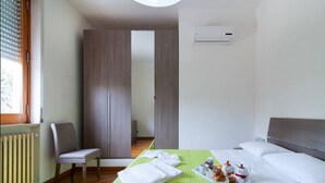 Una habitación de hotel con una cama, una silla, un radiador y un armario.