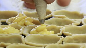 Una persona introduce relleno amarillo en una pieza de pastelería.