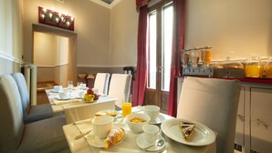 A breakfast setup with a table set for two, including plates, bowls, cups, and a glass of orange juice. - Boutique B&B Torre De' Conti (Florence)