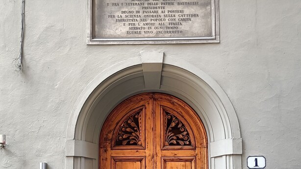 A building entrance with a wooden double door, a plaque above, and a number 1 sign on the wall. - Boutique B&B Torre De' Conti (Florence)