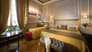 A hotel room with two beds, a desk, a chair, a suitcase, and a potted plant. - Boutique B&B Torre De' Conti (Florence)