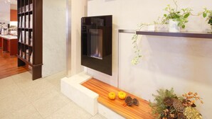A modern interior with a fireplace, wooden shelves with plants, and a display of pumpkins and decorative items. - Hotel Garden Square Shizuoka (Shizuoka)