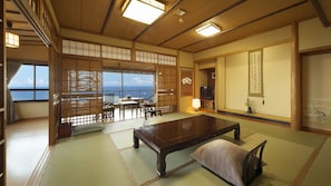 A traditional Japanese room with tatami flooring, a low table, and a view of the sea. - Chikurinan Mizuno (Atami)