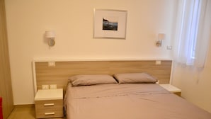 A hotel room with a bed, two bedside tables, a nightstand, and a wall-mounted picture. - Caudullo (Letojanni)